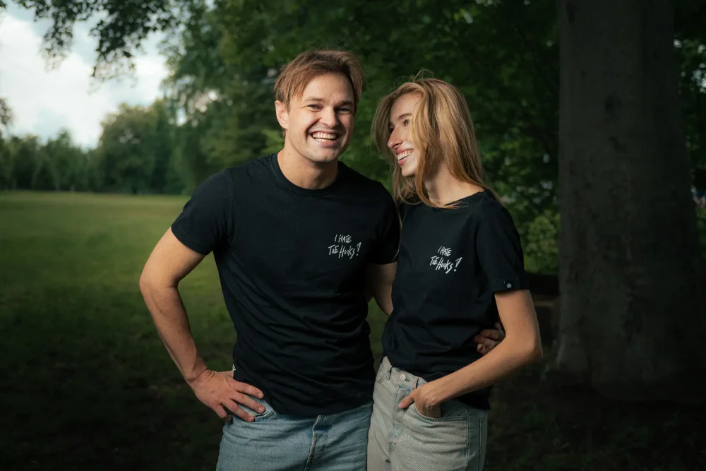 A man and a woman posing in the Adam Ondra "I hate toehooks" black T-shirt, front side
