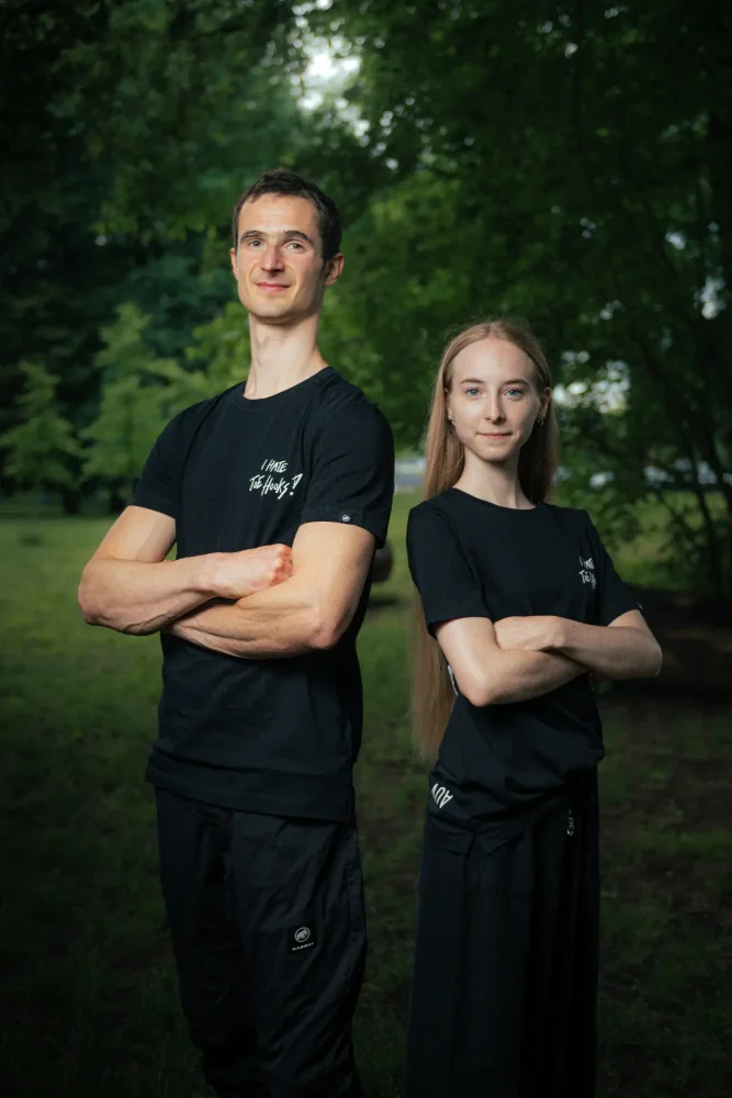 Adam Ondra and a woman model posing in the AO "I hate toehooks" black T-shirt, front side