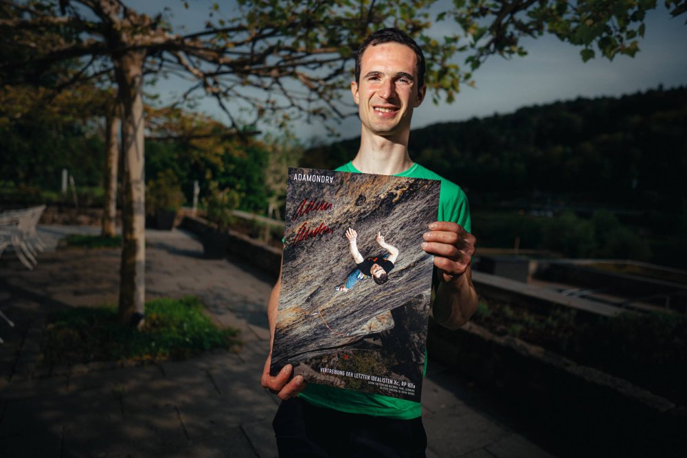 Adam Ondra holding his signed Saxony Sandstone poster